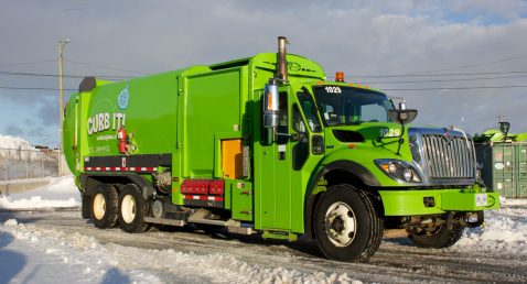 Green garbage truck on a winter day.