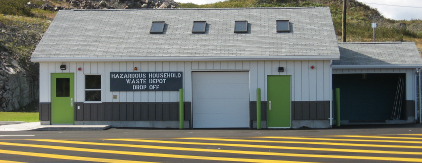 Household hazardous waste building. Upper siding is white and lower siding is dark grey. Has 2 light green doors and a white garage door.